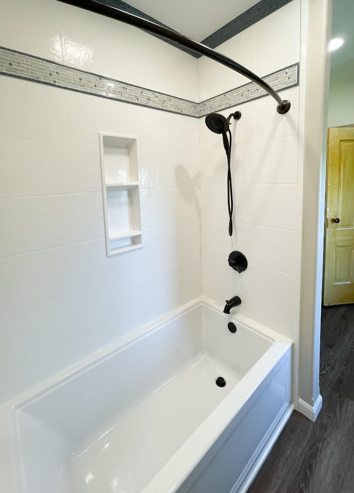 Modern bathtub and shower combo remodel with solid-surface wall panels and matte black fixtures installed by AZ Fast Bath in the East Valley, Arizona.